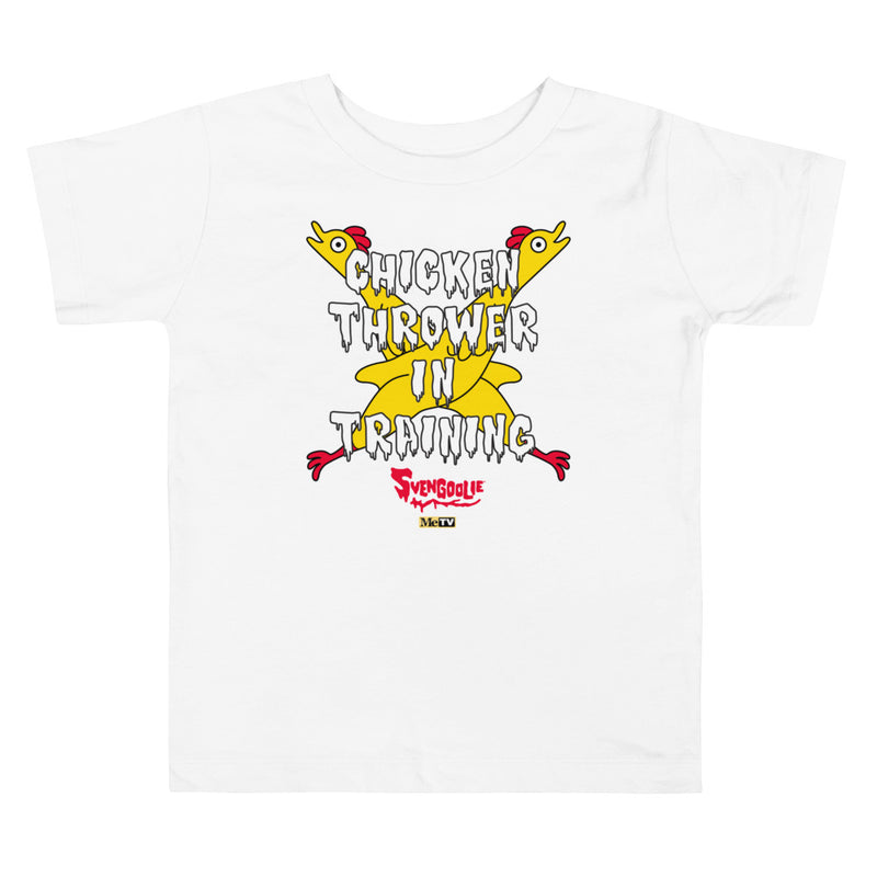 White toddler t-shirt with yellow cartoon chickens crossed over the text "CHICKEN THROWER IN TRAINING" and a red "Svengoolie" logo.