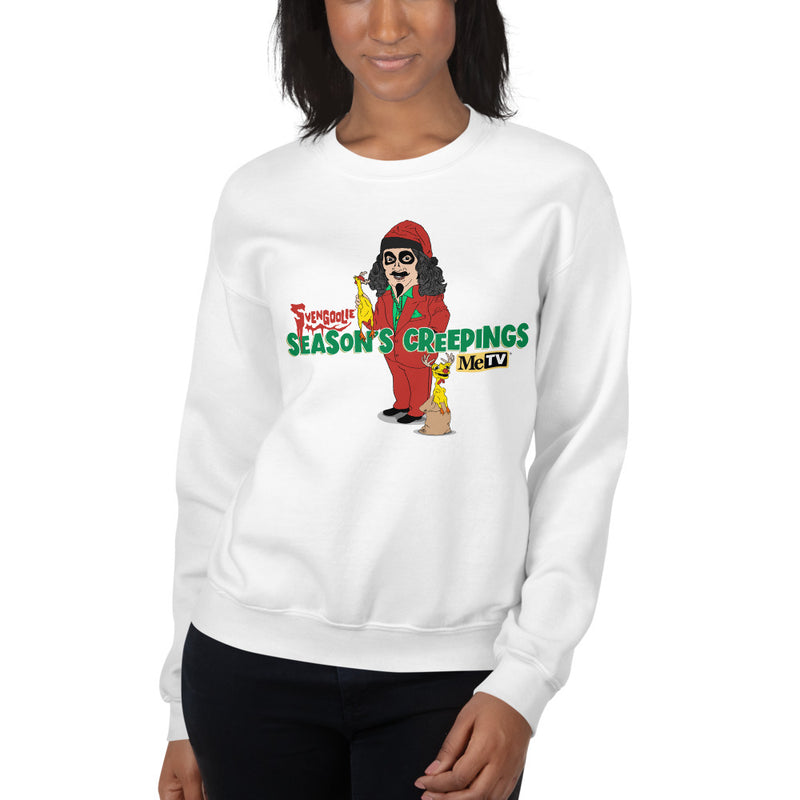 Woman wearing white crewneck sweatshirt with cartoon Svengoolie in red suit holding a chicken, 'Season's Creepings' text and MeTV logo