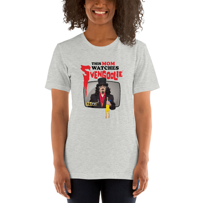 Model wearing gray t-shirt featuring Svengoolie holding a rubber chicken with the text 'This Mom Watches Svengoolie' in black and red above it.