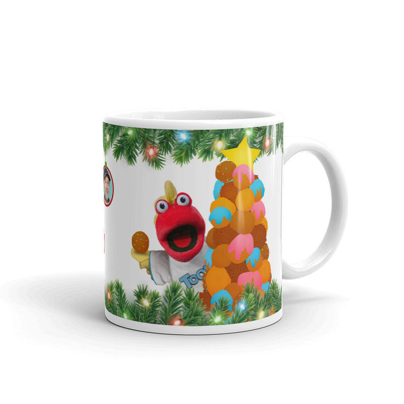 White ceramic mug with green pine garland and string lights; red sock puppet holds a cookie beside a stacked cookie tree topped with a yellow star.