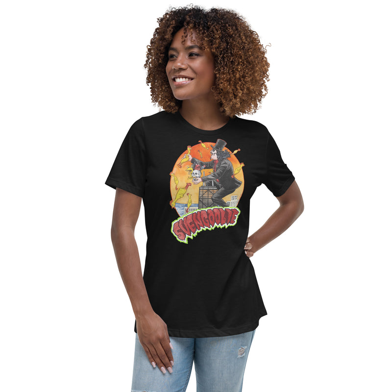 Black women's t-shirt with Svengoolie in top hat and black suit, at the top of a skyscraper, holding a skull, surrounded by rubber chickens, with 'SVENGOOLIE' in red letters over an orange sunset city.